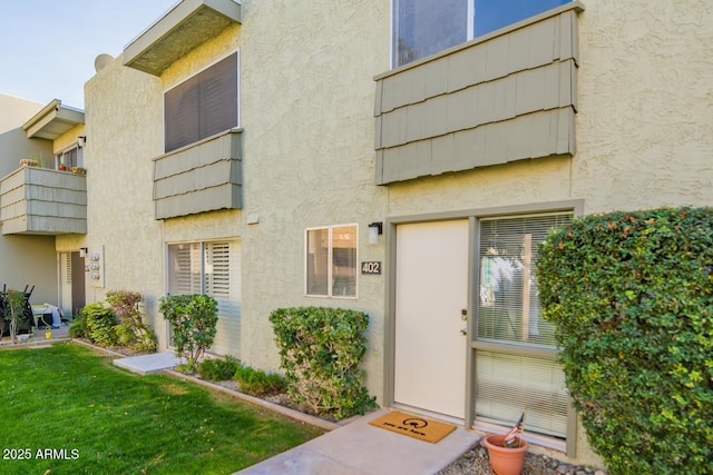 property entrance featuring a lawn and stucco siding