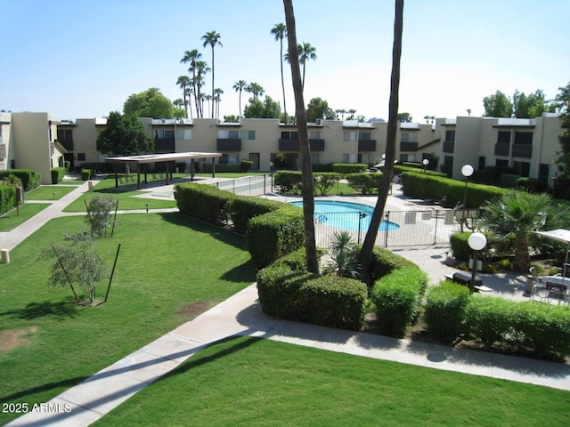 view of community featuring a pool, a residential view, a yard, and fence