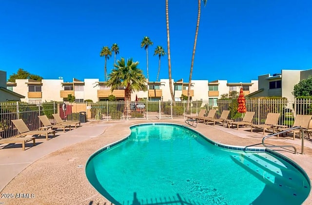 community pool featuring a residential view, fence, and a patio