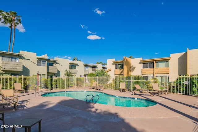 community pool featuring a patio area, a residential view, and fence