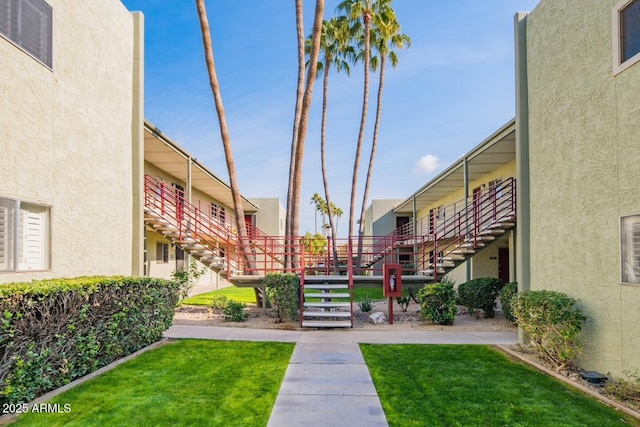 view of home's community with stairway and a lawn