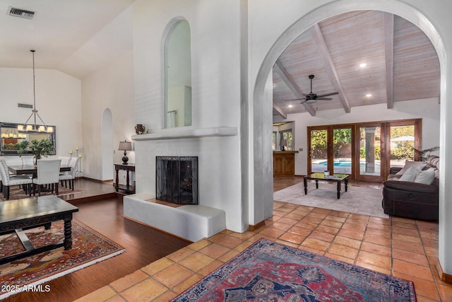 living room featuring high vaulted ceiling, beamed ceiling, wood-type flooring, ceiling fan, and wooden ceiling