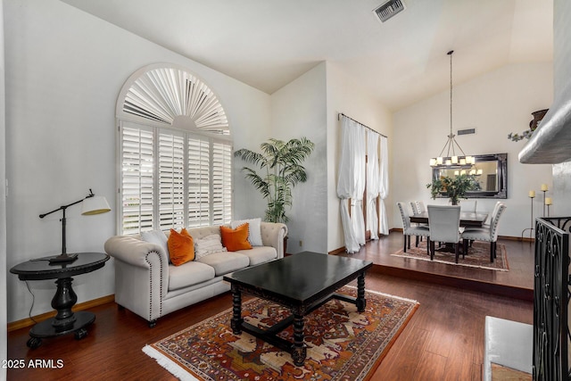 living room featuring dark hardwood / wood-style floors, a chandelier, and vaulted ceiling