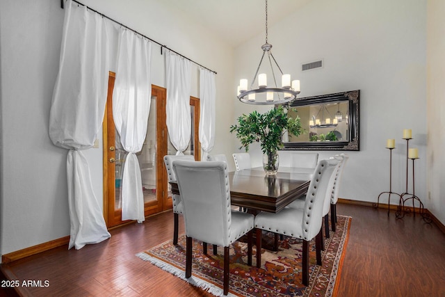 dining area with vaulted ceiling, dark hardwood / wood-style floors, and an inviting chandelier