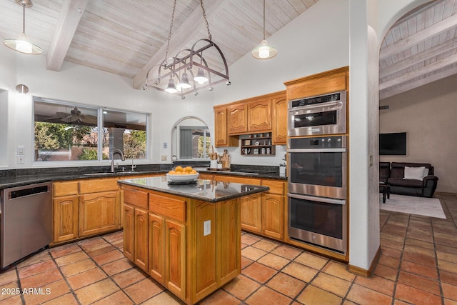 kitchen with sink, a center island, hanging light fixtures, appliances with stainless steel finishes, and beam ceiling