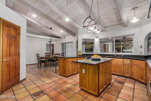 kitchen featuring sink, a breakfast bar area, lofted ceiling with beams, a kitchen island, and pendant lighting