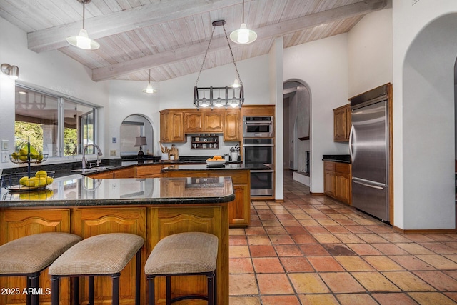 kitchen with sink, a breakfast bar, appliances with stainless steel finishes, decorative light fixtures, and kitchen peninsula