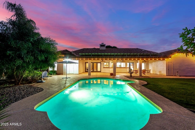 pool at dusk with a patio and a yard