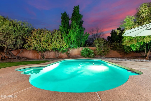 pool at dusk featuring a patio