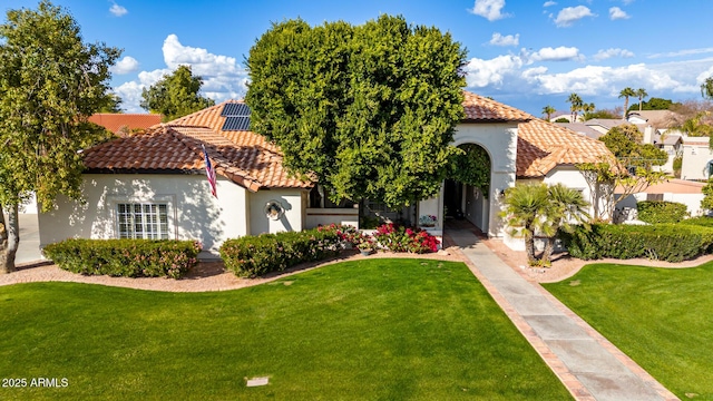 mediterranean / spanish house with a front yard and solar panels