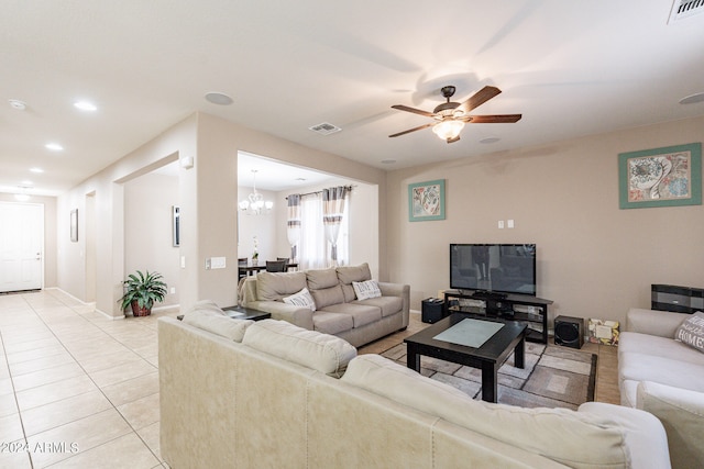 tiled living room with ceiling fan with notable chandelier