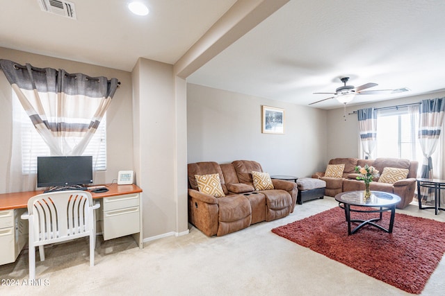 living room with built in desk, ceiling fan, and light carpet