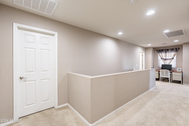 hallway with visible vents, an upstairs landing, and carpet flooring