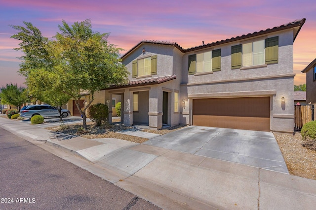 mediterranean / spanish-style house featuring a tile roof, concrete driveway, a garage, and stucco siding