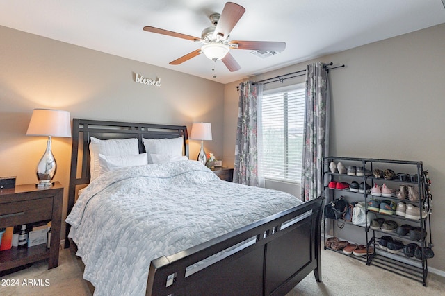 bedroom with light carpet, visible vents, and a ceiling fan