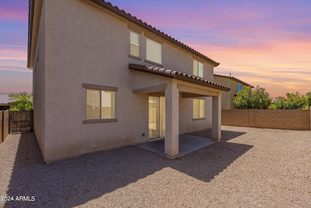 back house at dusk with a patio area and a pergola