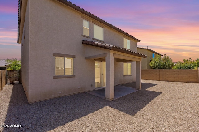 rear view of house featuring a patio area, stucco siding, a tiled roof, and a fenced backyard