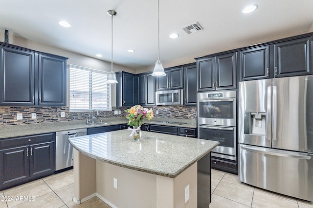 kitchen featuring pendant lighting, stainless steel appliances, a kitchen island, sink, and light stone countertops