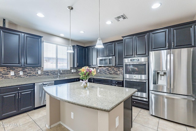 kitchen featuring visible vents, light stone counters, backsplash, a center island, and appliances with stainless steel finishes