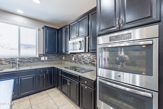 kitchen with tasteful backsplash, light stone countertops, stainless steel appliances, and sink