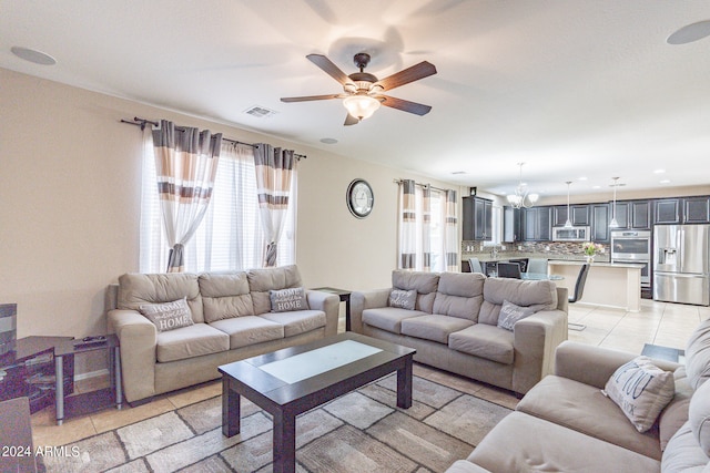 living room with a wealth of natural light, light tile patterned floors, and ceiling fan with notable chandelier