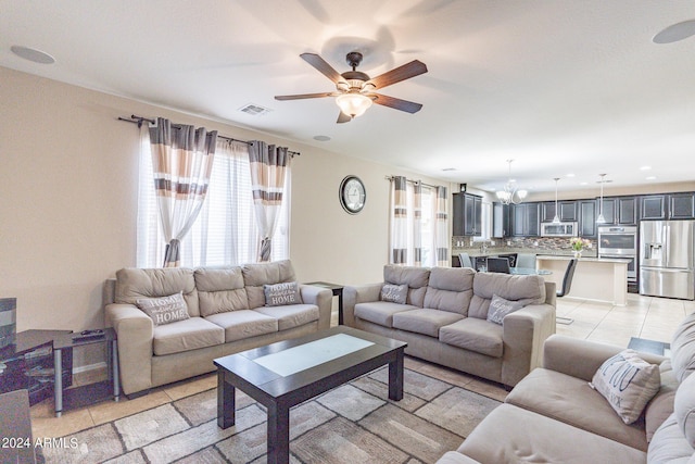 living area with light tile patterned floors, ceiling fan with notable chandelier, and visible vents