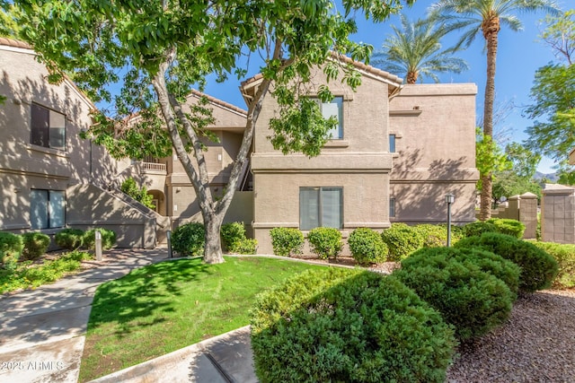 view of front of property with stucco siding, a front yard, and a tiled roof