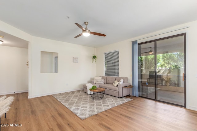 living area featuring baseboards, wood finished floors, and a ceiling fan