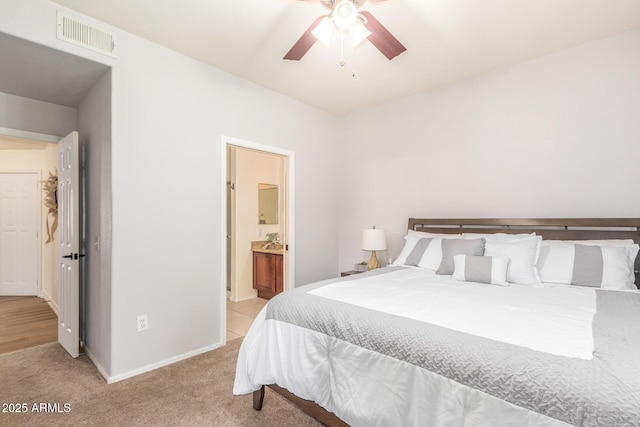 bedroom with visible vents, light carpet, a ceiling fan, ensuite bathroom, and baseboards