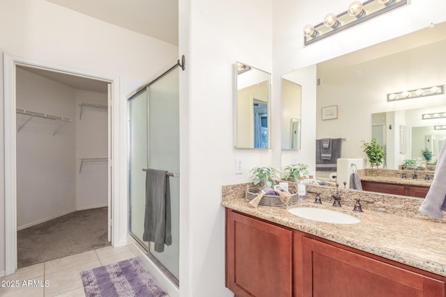 full bath featuring tile patterned flooring, a shower stall, a spacious closet, and vanity