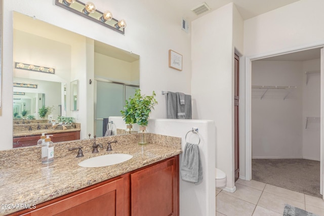 full bath featuring tile patterned flooring, a walk in closet, visible vents, and a stall shower