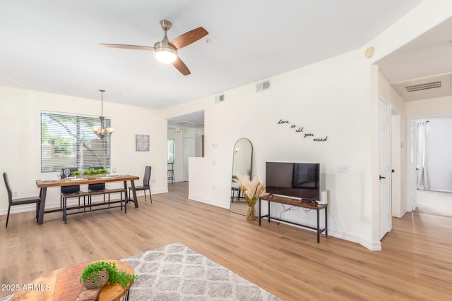 living room featuring visible vents, light wood-style flooring, and ceiling fan with notable chandelier