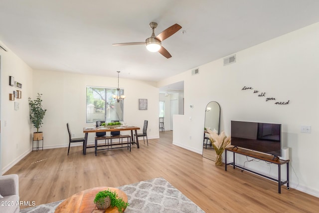 dining room featuring visible vents, ceiling fan with notable chandelier, baseboards, and light wood-style floors