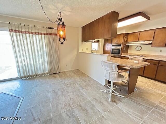 3242 W Christy Dr, Phoenix, AZ 85029 - kitchen featuring light countertops, oven, under cabinet range hood, a sink, and brown cabinets