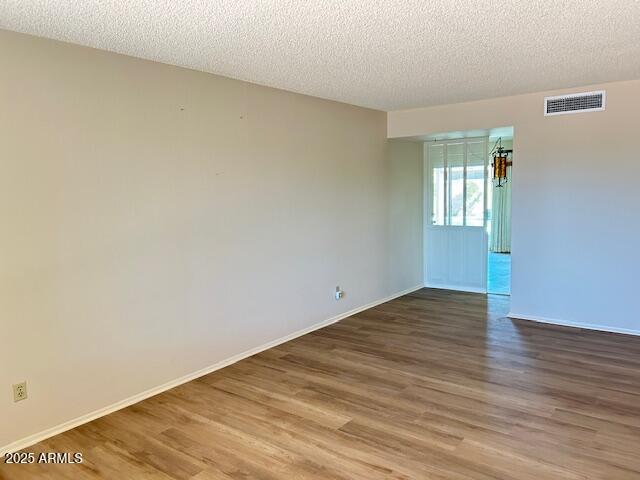 3242 W Christy Dr, Phoenix, AZ 85029 - spare room with baseboards, visible vents, wood finished floors, and a textured ceiling