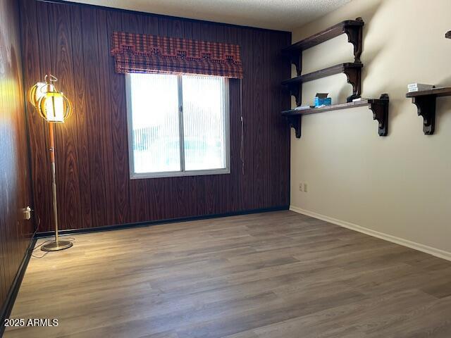 3242 W Christy Dr, Phoenix, AZ 85029 - spare room with baseboards, wood finished floors, and wooden walls