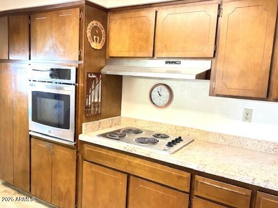 3242 W Christy Dr, Phoenix, AZ 85029 - kitchen with brown cabinets, electric cooktop, stainless steel oven, and under cabinet range hood