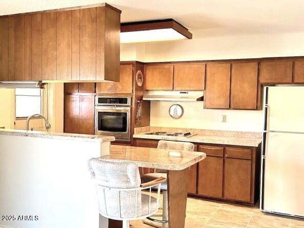 3242 W Christy Dr, Phoenix, AZ 85029 - kitchen with light countertops, a sink, brown cabinetry, under cabinet range hood, and stainless steel appliances