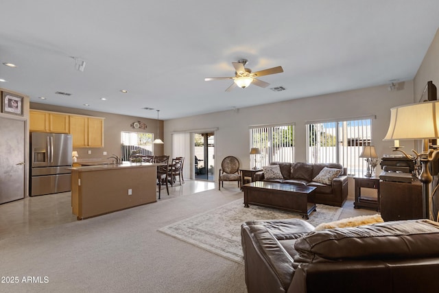 carpeted living room featuring ceiling fan and sink