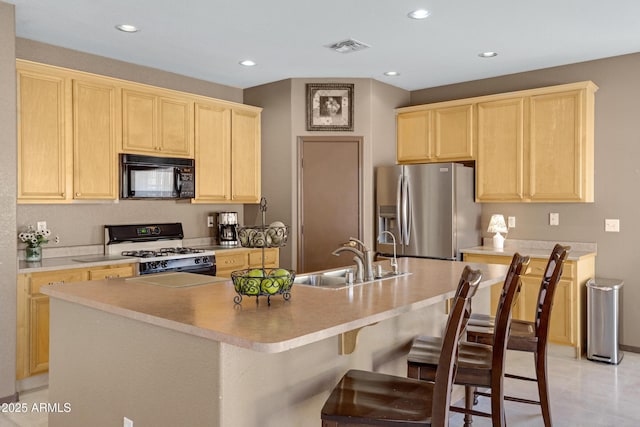 kitchen featuring stainless steel fridge with ice dispenser, light brown cabinets, a kitchen island with sink, gas range oven, and sink