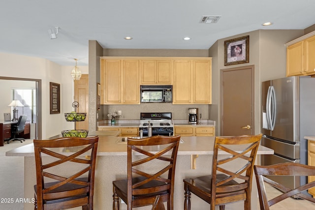 kitchen featuring a kitchen bar, light brown cabinetry, kitchen peninsula, stainless steel refrigerator, and white range with gas stovetop