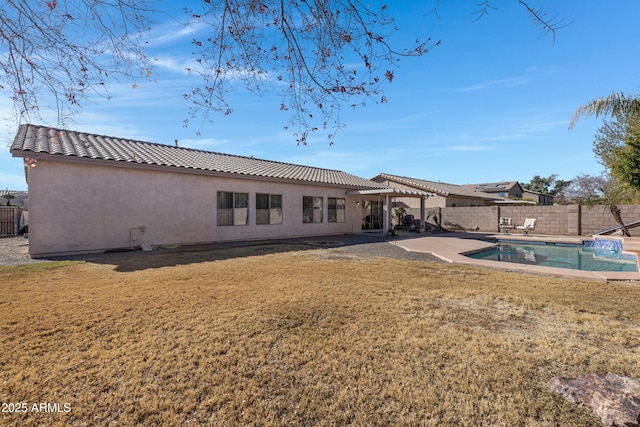 back of property featuring a fenced in pool, a yard, and a patio