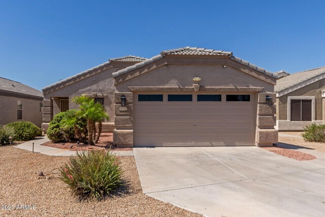 12132 W Caribbean Ln, El Mirage, AZ 85335 - view of front of home featuring an attached garage, driveway, a tile roof, and stucco siding