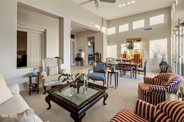 carpeted living room featuring a towering ceiling and ceiling fan