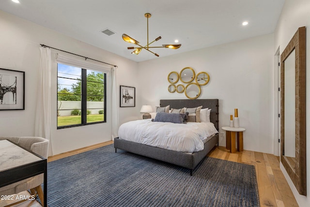 bedroom with wood-type flooring and a notable chandelier