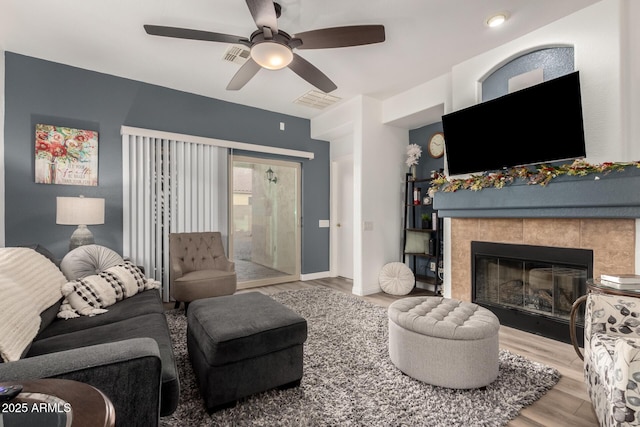 living room featuring ceiling fan, hardwood / wood-style floors, and a fireplace