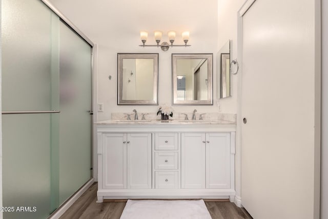 bathroom featuring wood-type flooring, a shower with door, and vanity