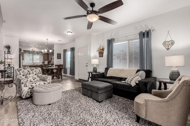 living room with ceiling fan with notable chandelier and hardwood / wood-style floors