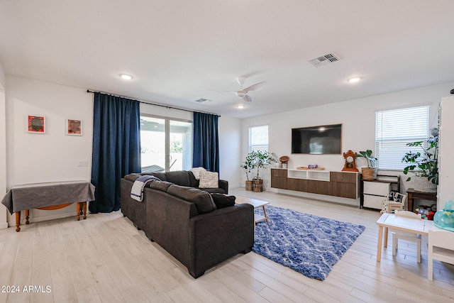 living room with light hardwood / wood-style flooring, ceiling fan, and a fireplace