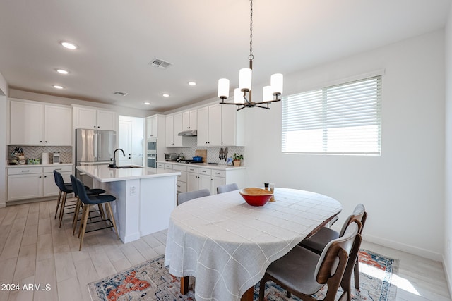 dining space featuring an inviting chandelier, light wood-type flooring, and sink